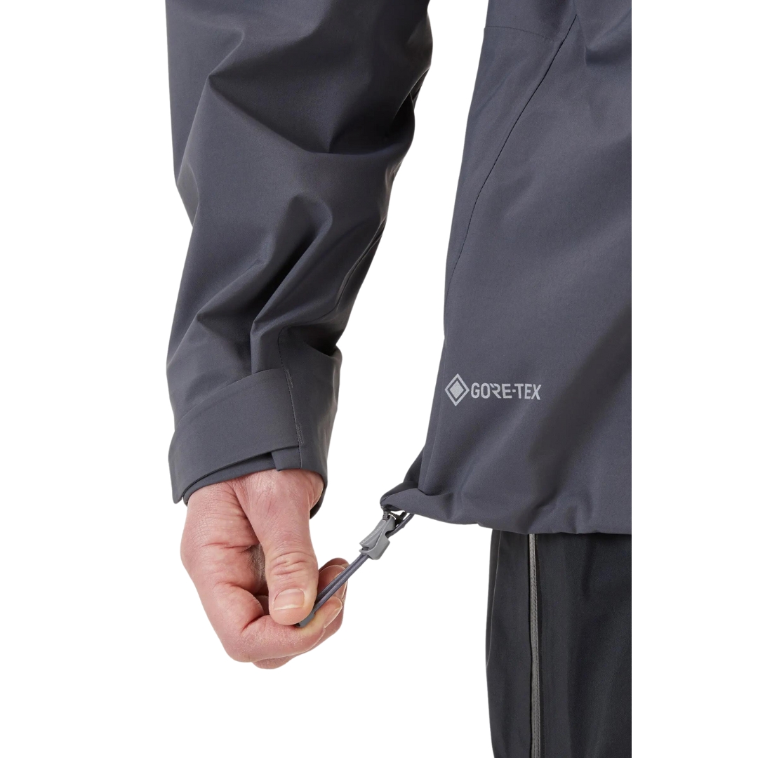 COQUILLE RAB KANGRI GORE-TEX POUR HOMME couleur graphene vu du manteau gris fonbcé et détails orange porté par un homme vu en gros plan sur le cordon de serrage a l'ourlet