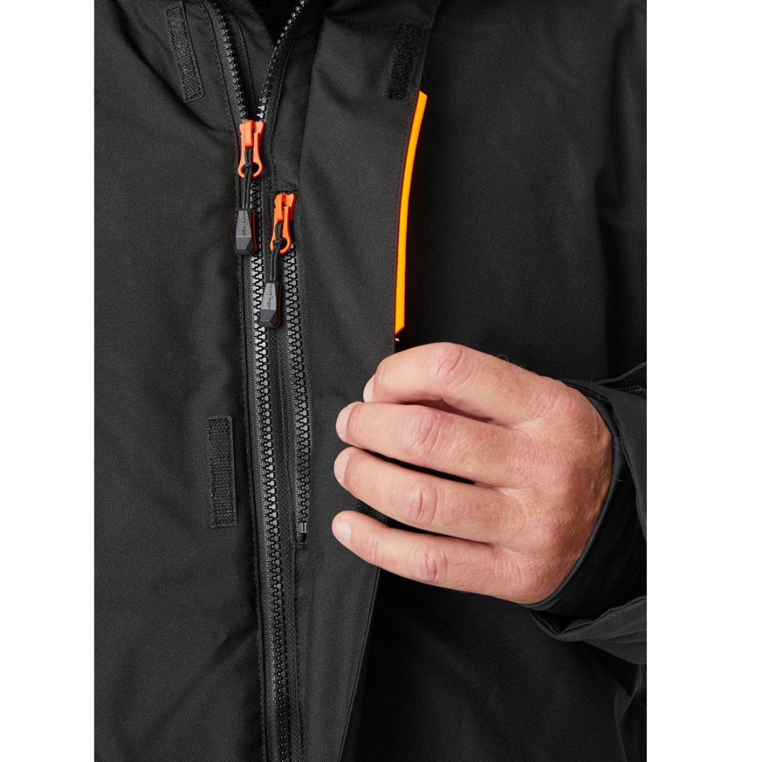 MANTEAU DE TRAVAIL ISOLÉ HELLY HANSEN WORKWEAR KENSINGTON POUR HOMME couleur black vu du manteau noir avec détails orange fluo porté par un homme vu en gros plan sur la fermeture éclair principale