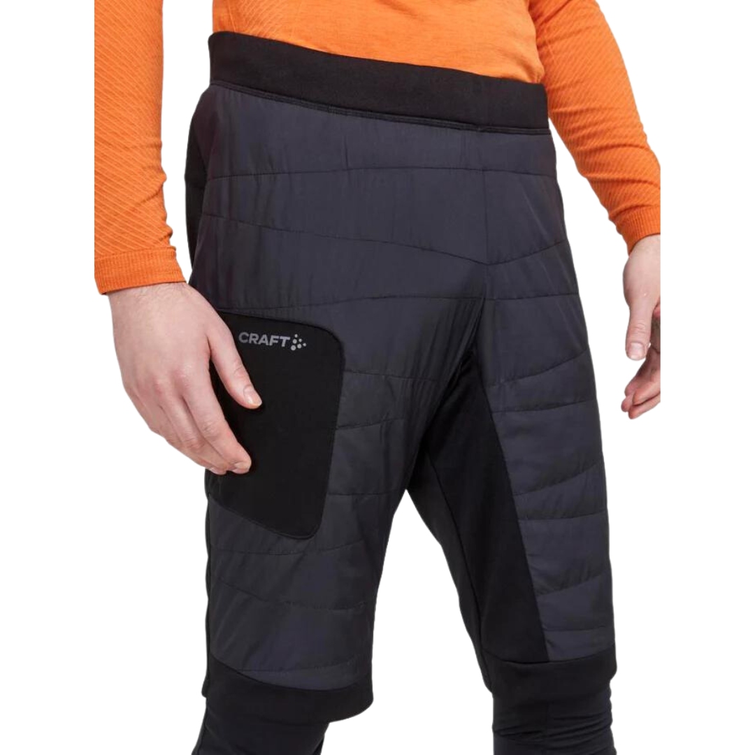 SHORT ISOLÉ POUR SKI DE FOND CRAGT CORE NORDIC TRAINING INSULATE POUR HOMME COULEUR BLACK VU DU SHORT NOIR PORTÉ PAR UN HOMME VU DE LA TAILLE AUX GENOUX DE PROFIL DROIT