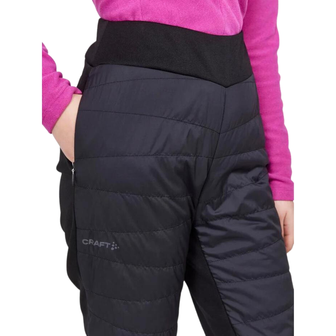 PANTALON ISOLÉ DE SKI DE FOND CRAFT CORE NORDIC TRAINING INSULATE POUR FEMME COULEUR BLACK VU DU PANTALON NOIR PORTÉ PAR UNE FEMME VUE EN GROS PLAN SUR LA HANCHE DROITE AVEC LA MAIN DANS LA POCHE LATÉRALE