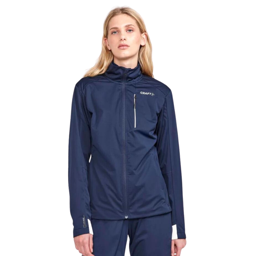 MANTEAU DE SKI DE FOND CRAFT ADV NORDIC TRAINING 2 POUR FEMME couleur blaze vu du manteau bleu marin doncé avec détails blanc porté par une femme vue de la tête aux cuisses de face