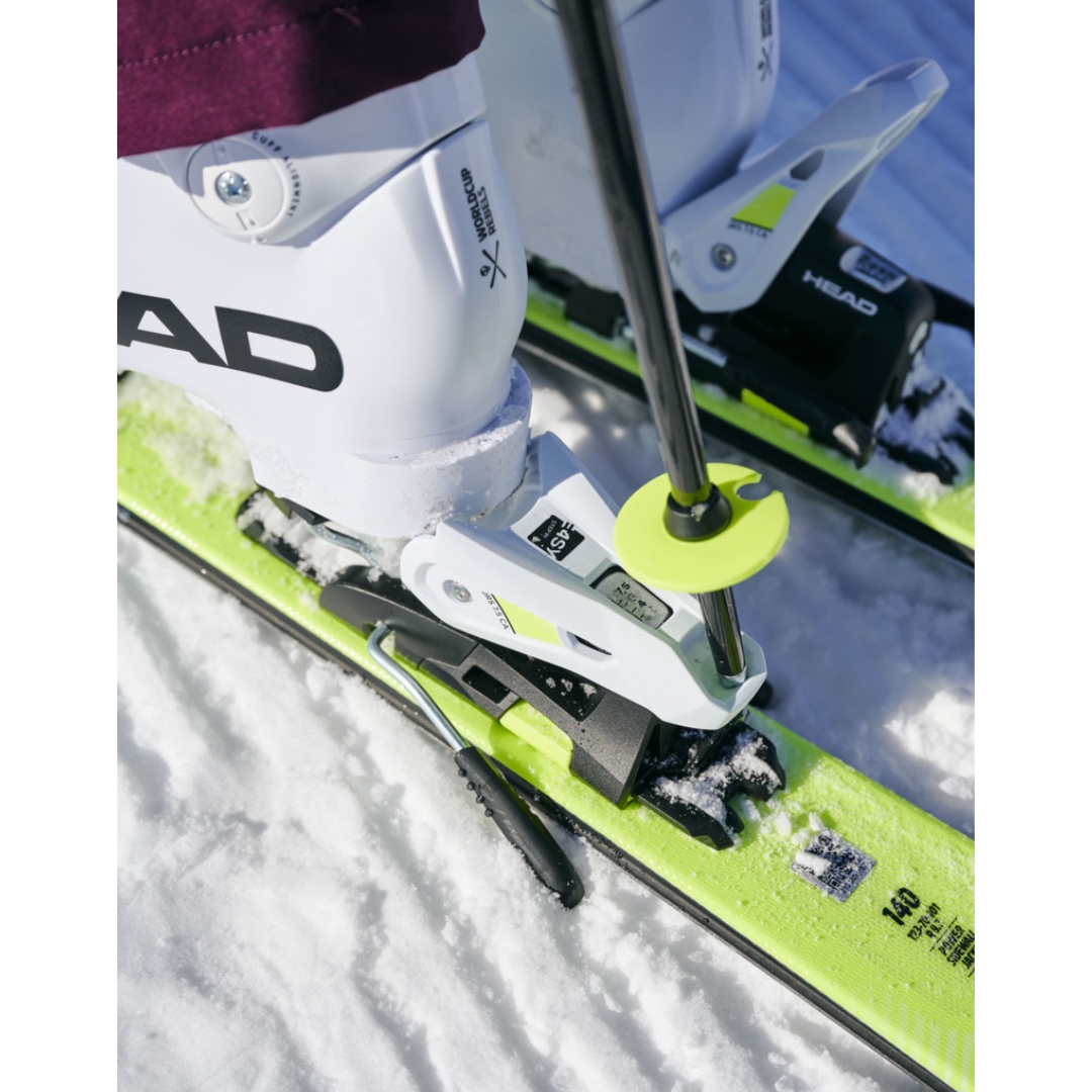 BÂTON AJUSTABLE DE SKI ALPIN HEAD SUPERSHAPE TEAM POUR ENFANT couleur white/black/speed blue utilisé par un skieur qui déclipse ses bottes sur les fixations