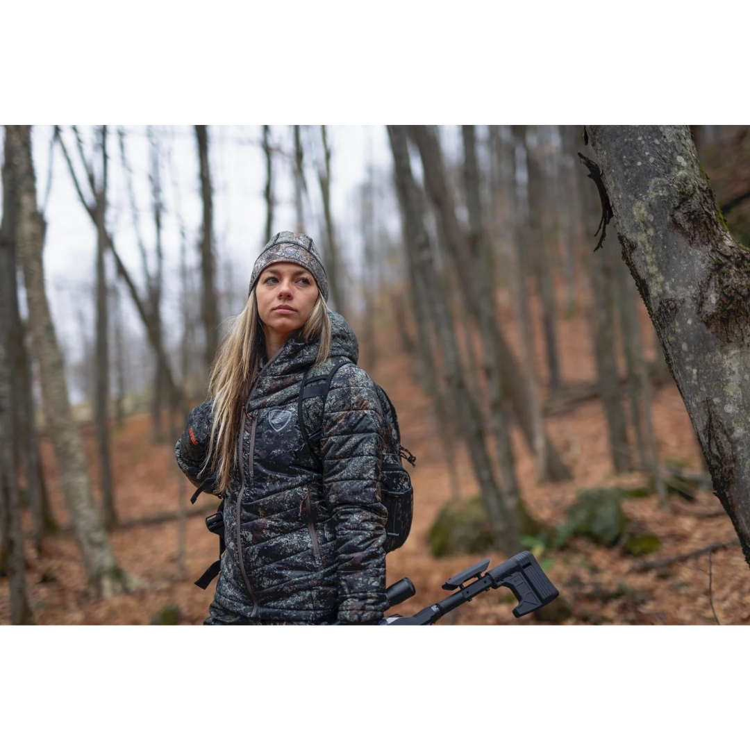 MANTEAU DE CHASSE SPORTCHIEF WILSON POUR FEMME COULEUR THE RIPPER VU DU MANTEAU À IMPRIMÉ CAMOUFLAGE TON DE TERRE PORTÉ PAR UNE FEMME VUE DASN LA FORET DE FACE