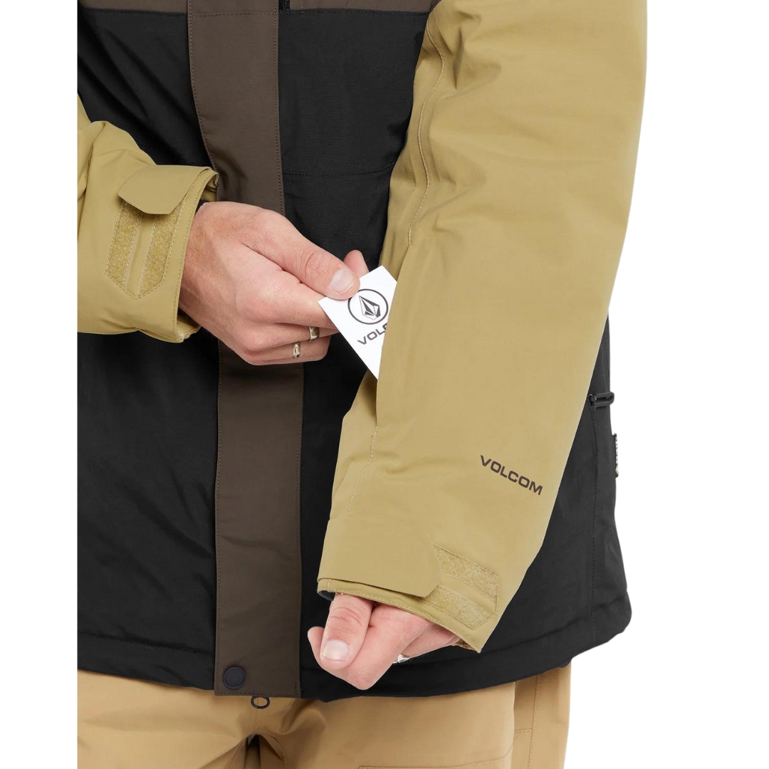 MANTEAU DE SKI EN GORETEX VOLCOM L POUR HOMME couleur brn-brown vu du manteau brun, noir et beige porté par un homme qui range une carte dans la poche sur la manche