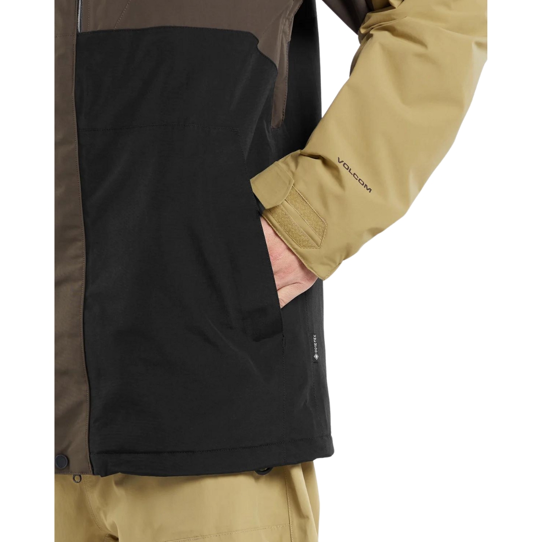 MANTEAU DE SKI EN GORETEX VOLCOM L POUR HOMME couleur brn-brown vu du manteau brun, noir et beige porté par un homme qui a la main dans la poche latérale