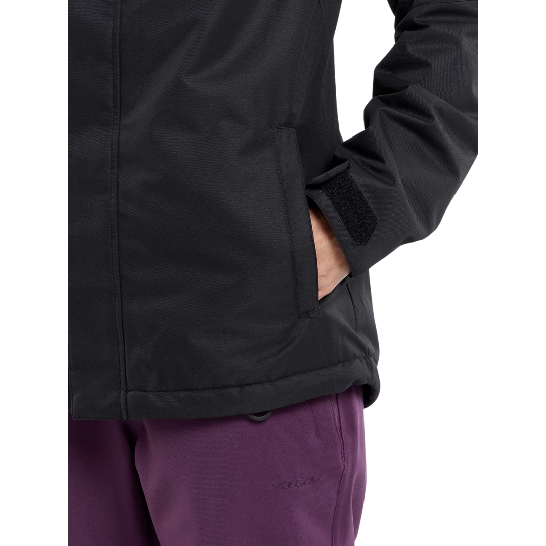 MANTEAU DE SKI ISOLÉ VOLCOM BOLT POUR FEMME couleur BLK-BLACK vu du manteau noir porté par une femme vue en gros plan de sa main dans la poche latérale