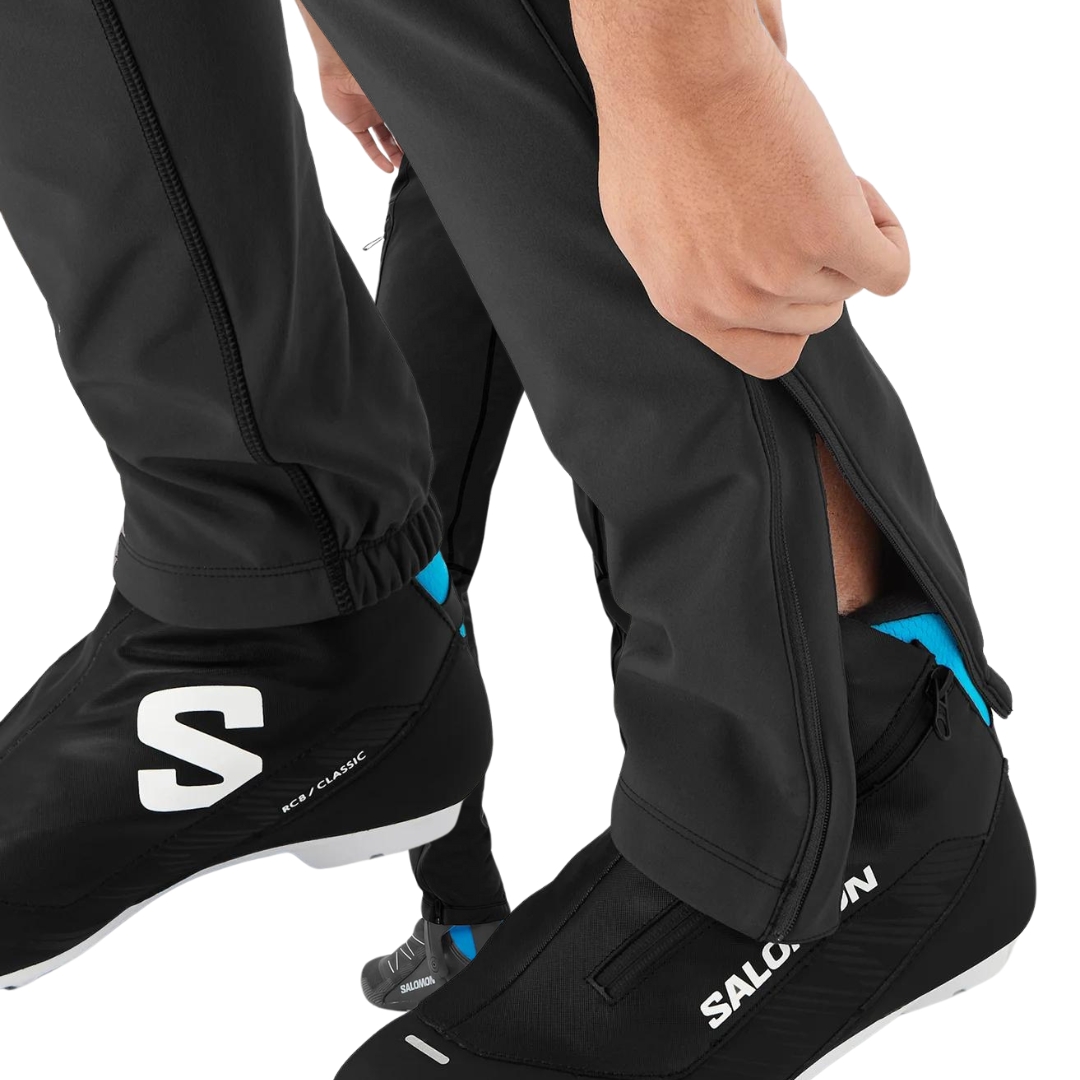 PANTALON DE NEIGE SALOMON RS WARM SOFTSHELL POUR HOMME couleur deep black vu du pantalon noir porté par un homme qui refeme la fermeture éclair au bas de la jambe