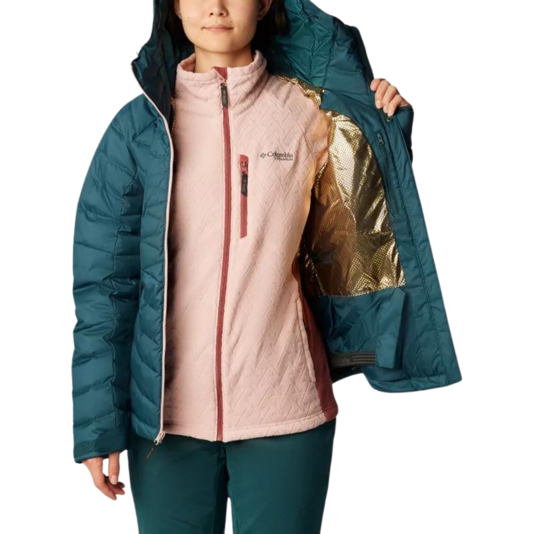 MANTEAU DE SKI ALPIN ISOLÉ EN DUVET COLUMBIA DROARING FORK POUR FEMME couleur 414-NIGHT WAVE vu du manteau turquoise foncé avec fermeture éclair rose pale porté par une femme vue de face avec le manteau ouvert et elle montre un pan intérieur