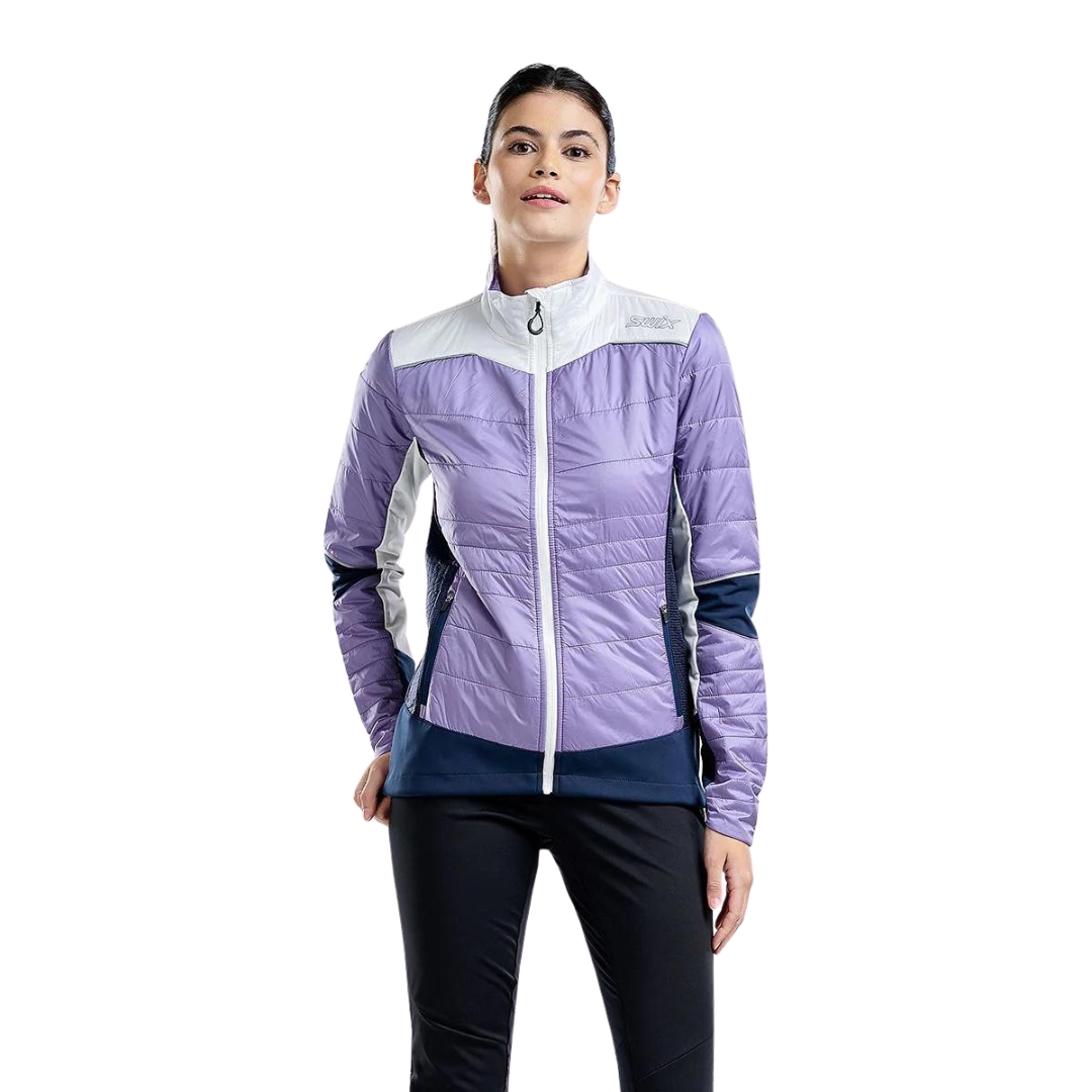 MANTEAU D'ENTRAINEMENT SWIX NAVADO HYBRID POUR FEMME couleur lavender vu du manteau lilas, bleu marin et blanc porté par une femme vue de la tête aux cuisses de face