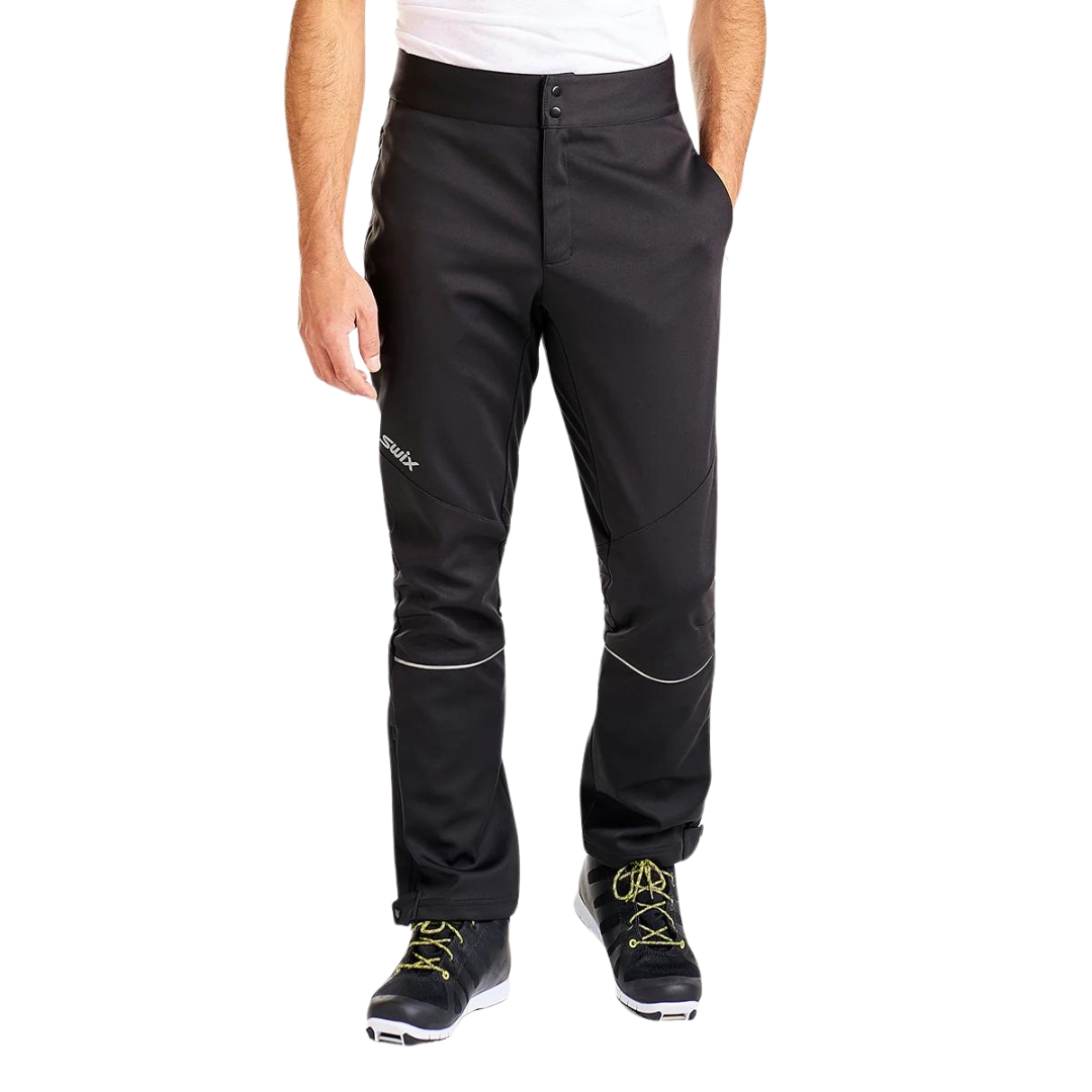 PANTALON D'ENTRAINEMENT COQUILLE SOUPLE SWIX TOKKE POUR HOMMEPANTALON D'ENTRAINEMENT COQUILLE SOUPLE SWIX TOKKE POUR HOMME couleur 10000-BLACK vu du pantalon noir porté par un homme vu de la taille aux pieds de face avec une main dans la poche latérale