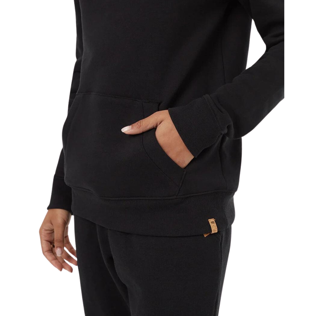 CHANDAIL À CAPUCHON TENTREE TREEFLEECE BANSHEE POUR FEMME couleur meteorite black vu du chandail noir porté par une femme vu en gros plan sur la main dans la poche kangourou de profil gauche