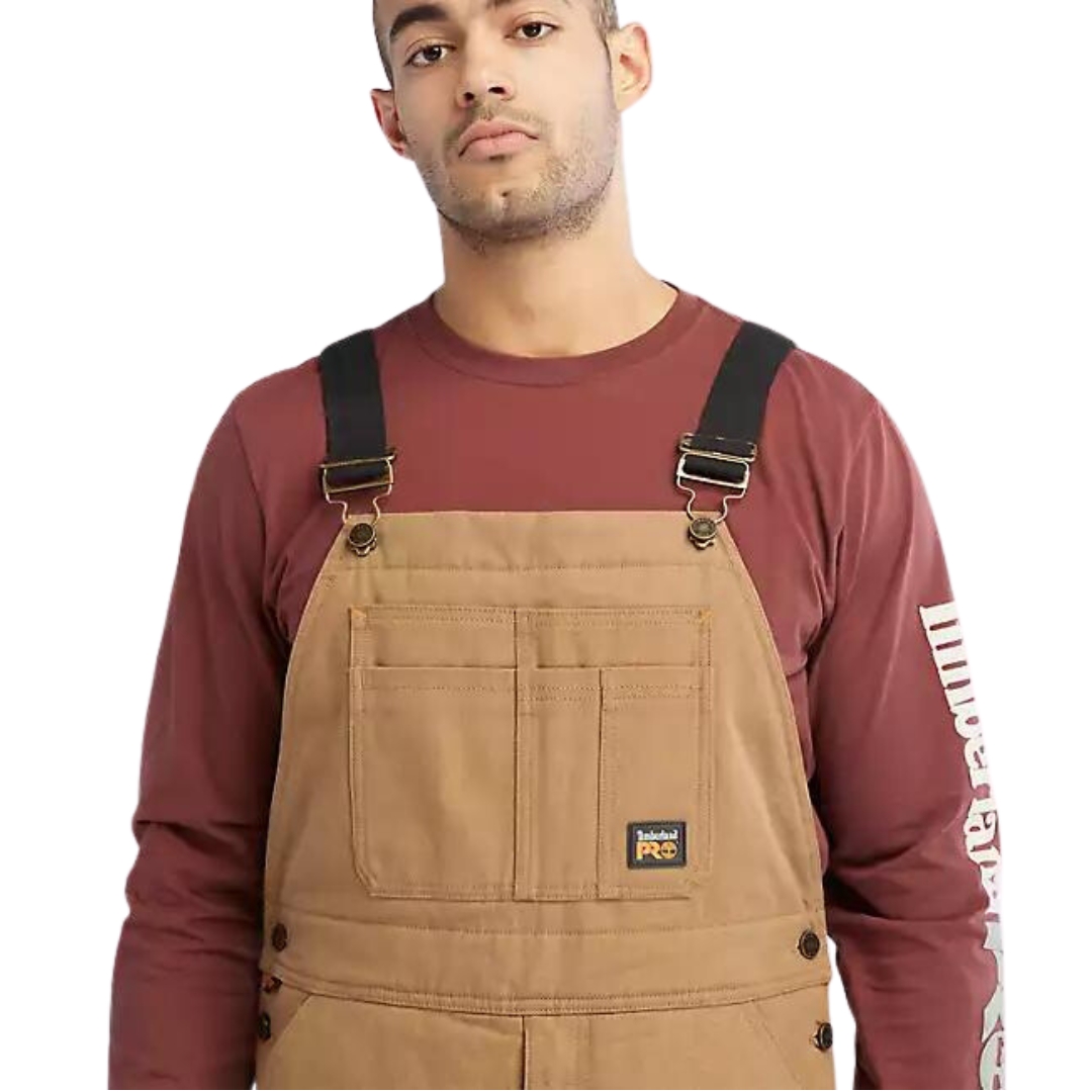 salopette isolée timberland gritman pour homme couleur dark wheat vu de la salopette brune/beige portée par un homme vu en gros plan sur le haut avant de la salopette à bretelles noires