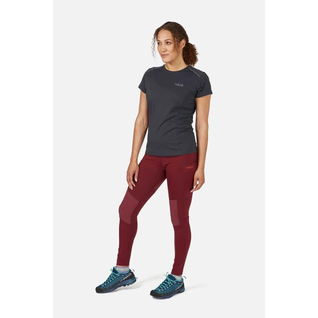 LEGGING D'ENTRAINEMENT RAB HORIZON POUR FEMME couleur Deep Heather porté par une femme vue de la tête aux pieds de face avec le legging moulant rouge brique logo et nom rab imprimé sur la poche de cuisse gauche visible aini que les renfort en tissus double densité aux genoux