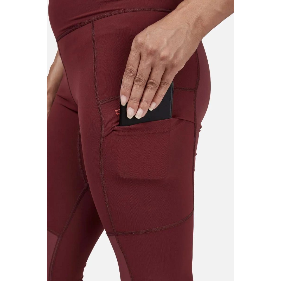 LEGGING D'ENTRAINEMENT RAB HORIZON POUR FEMME couleur Deep Heather porté par une femme qui glisse un téléphone cellulaire dans la poche de cuisse gauche