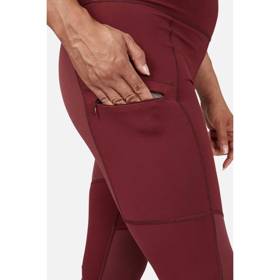 LEGGING D'ENTRAINEMENT RAB HORIZON POUR FEMME couleur Deep Heather porté par une femme qu iglisse sa main dans la poche de cuisse droite a fermeture éclair coutures plates visibles