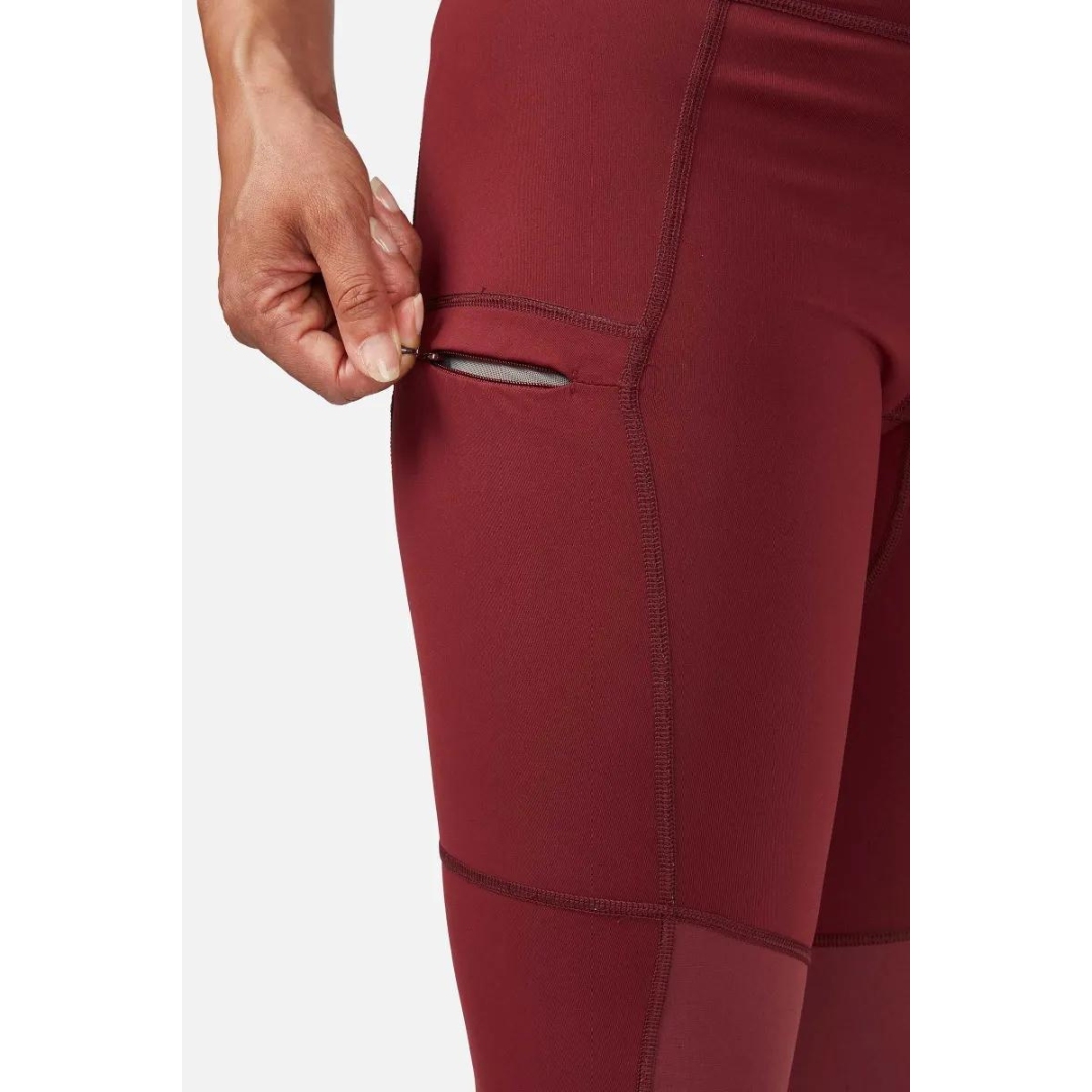 LEGGING D'ENTRAINEMENT RAB HORIZON POUR FEMME couleur Deep Heather porté par une femme qui montre la poche de cuisse à fermeture à glissière sur la cuisse doite du pantalon rouge brique