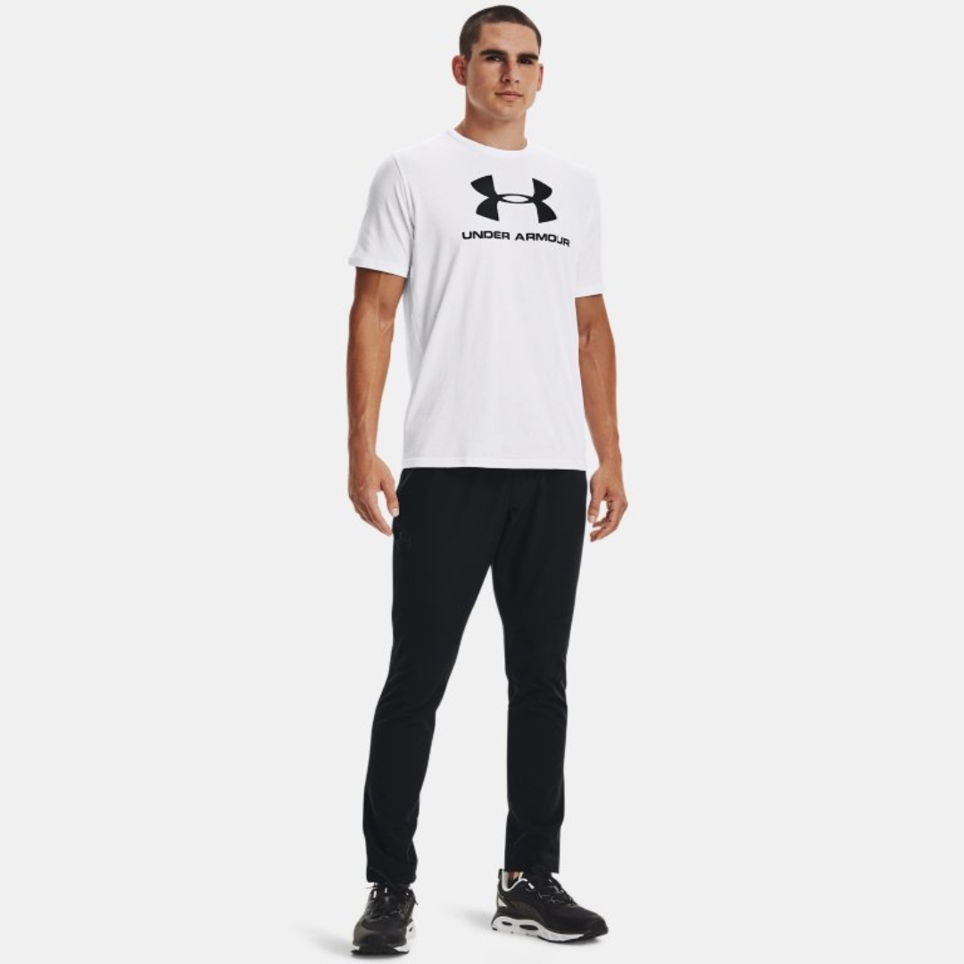 CHANDAIL À MANCHES COURTES UNDER ARMOUR UA SPORTSTYLE LOGO POUR HOMME COULEUR 100-WHITE/BLACK PORTÉ PAR UN HOMME VU DE LA TÊTE AUX PIEDS AVEC LE CHANDAIL BLANC À IMPRIMÉ NOIR