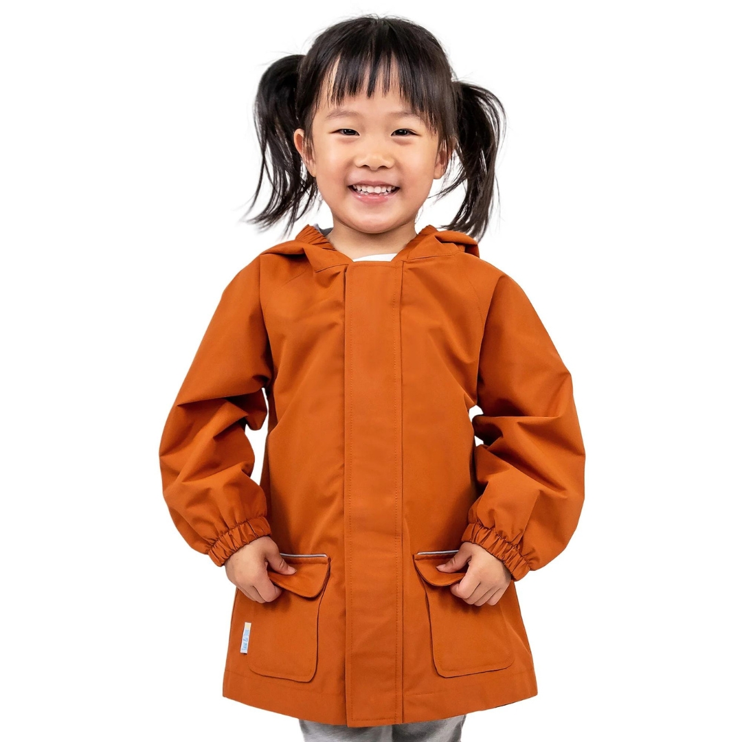 MANTEAU DE PLUIE JAN & JUL PUDDLE-DRY POUR ENFANT couleur TERRACOTTA vu du manteau orange brûlé porté par un enfant vue de la tête aux cuisses de face