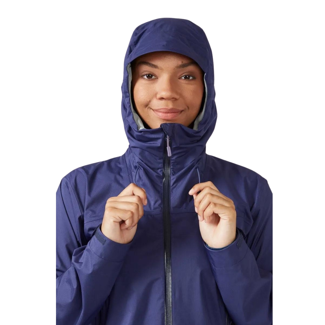 MANTEAU IMPERMÉABLE RAB DOWNPUR PLUS 2.0 POUR FEMME vu couleur PATRIOT BLUE vu du manteau bleu foncé porté par une femme vue en gros plan sur le capuchon et elle le reserre avec les cordon de serrage