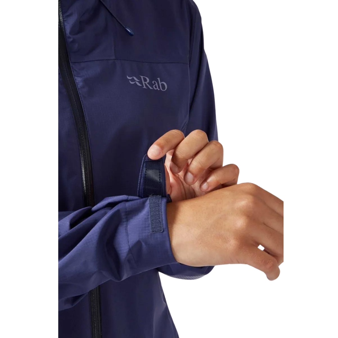 MANTEAU IMPERMÉABLE RAB DOWNPUR PLUS 2.0 POUR FEMME vu couleur PATRIOT BLUE vu du manteau bleu foncé porté par une femme vue ajustant le tour de poignet avec la bande velcro