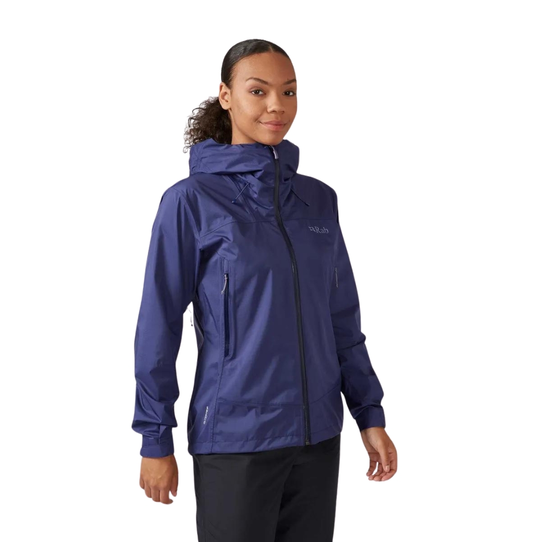 MANTEAU IMPERMÉABLE RAB DOWNPUR PLUS 2.0 POUR FEMME vu couleur PATRIOT BLUE vu du manteau bleu foncé porté par une femme vue de la tête aux cuisses de profil avant droit