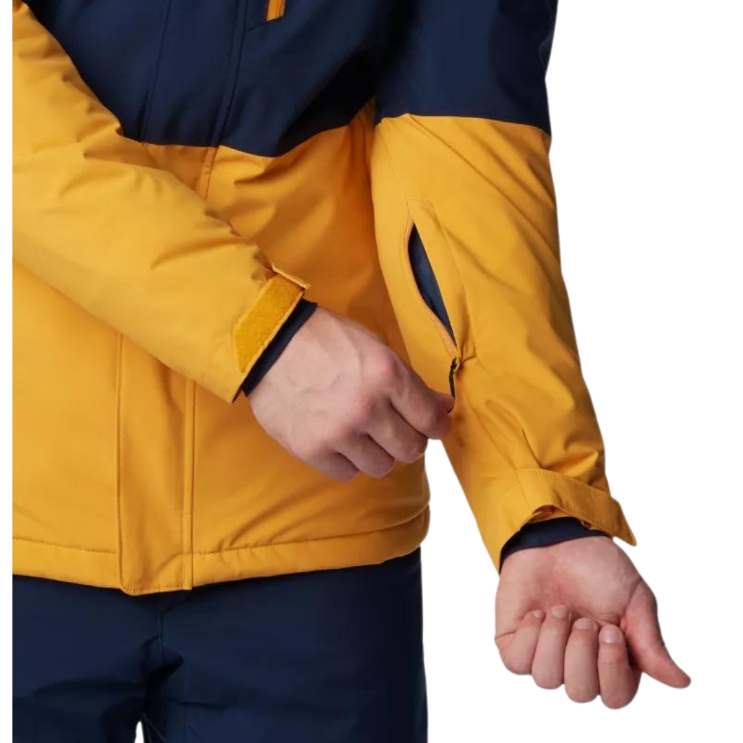 MANTEAU DE SKI ALPIN COLUMBIA WINTER DISTRICT II POUR HOMME couleur 756-RAW HONEY/COLLEGIATE navy vu du manteau bleu marin foncé et jaune ocre porté par un homme vu montrant la poche de manche pour passe de ski