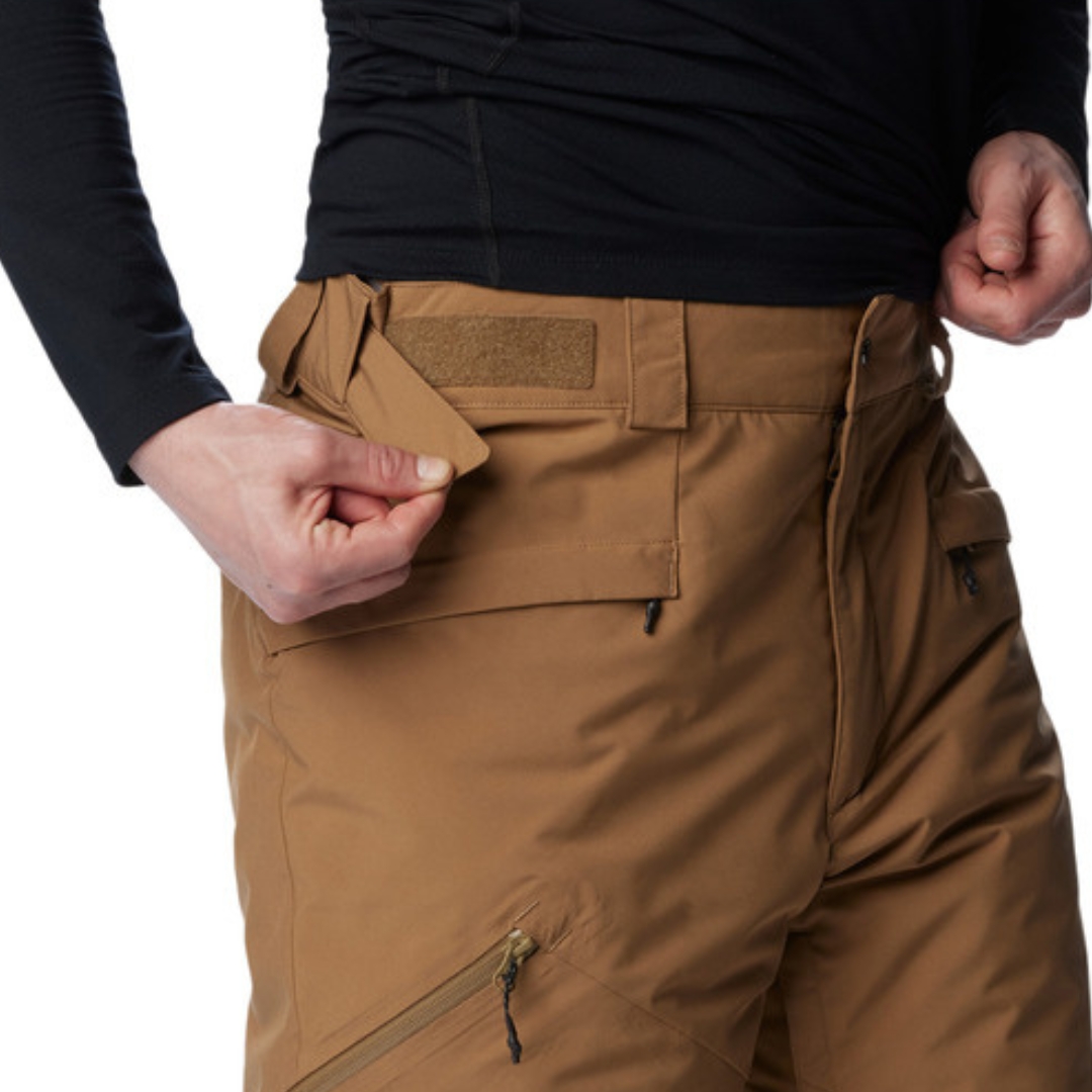 PANTALON DE NEIGE COLUMBIA KICK TURN III POUR HOMME couleur 257-DELTA vu du pantalon brun sable porté par un homme vu en gros plan sur le haut droit du pantalon l'homme montre la taille ajustable