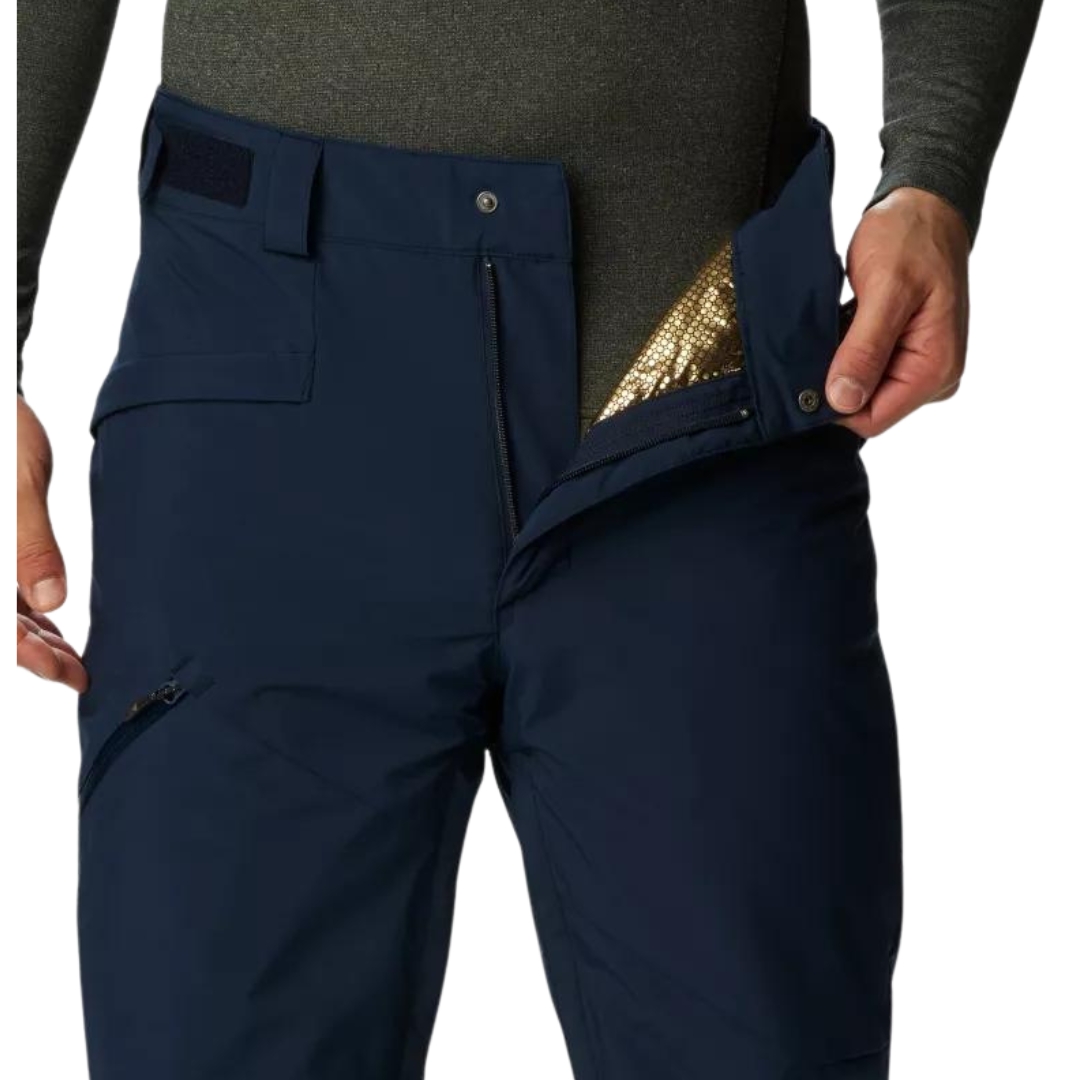 PANTALON DE NEIGE COLUMBIA KICK TURN III POUR HOMME couleur 464-COLLEGIATE NAVY vu du pantalon marine porté par un homme vu en gros plan sur le haut avant du pantalon l'homme montre l'intérieur du pantalon