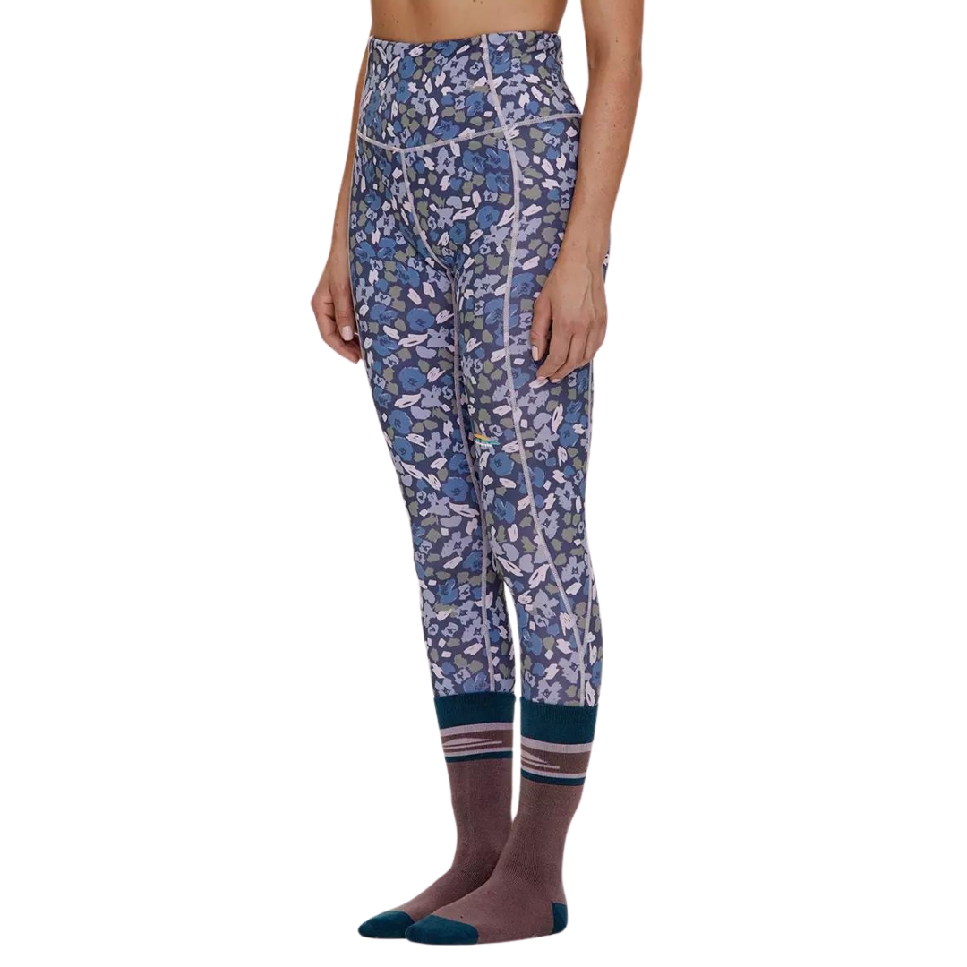 LEGGING COUCHE DE BASE CHLOROPHYLLE CHL2 POUR FEMME couleur FLEUR BLEU ODYSSÉE vu du legging bleu marin avec motif fleuraux abstrait dans les tons de bleu royal, lilas et vert olive porté par une femme vue de la taille aux pieds de profil avant gauche