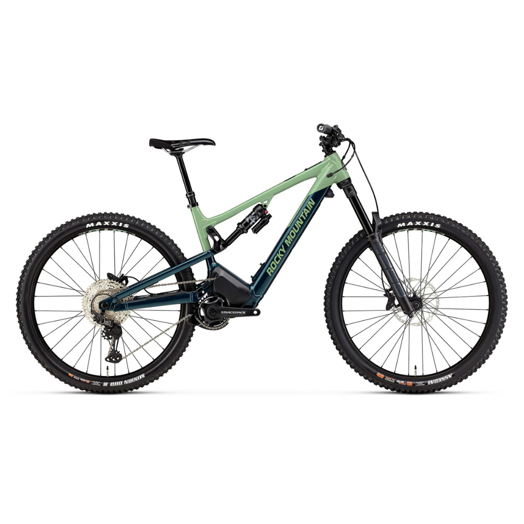 L'ALTITUDE POWERPLAY A50 SHIMANO est un VTT équipé de gros pneus à crampons Maxxis, d'une double suspension, de freins à disque et d'un guidon droit. Il est doté d'un cadre bicolore vert en haut et bleu foncé en bas.