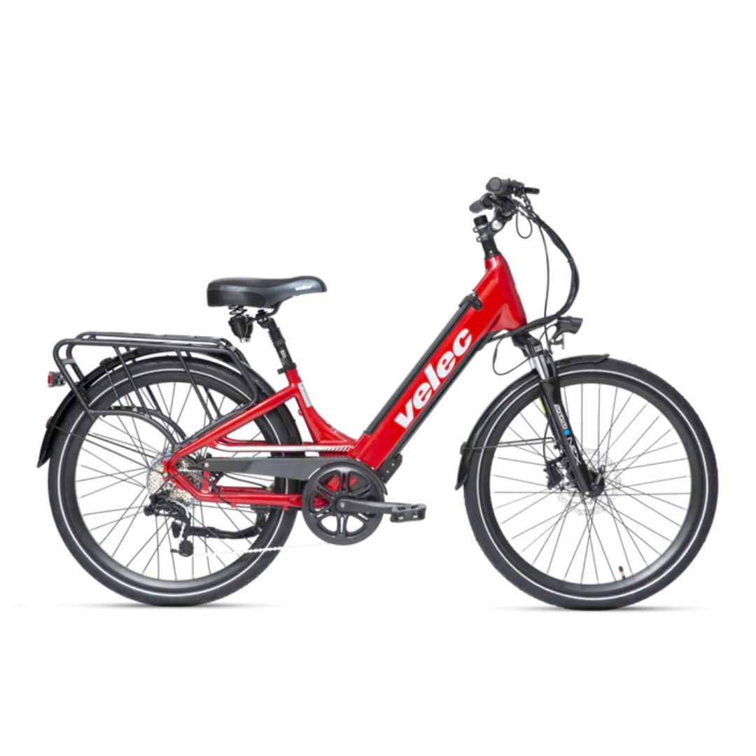 Un vélo électrique rouge avec un cadre à enjambement. Il est doté d'une selle noire rembourrée, d'un porte-bagages arrière, de garde-boue avant et arrière et d'une batterie visible sur le cadre avec le nom de marque « Velec ». Le vélo est équipé de freins à disque avant et arrière.
