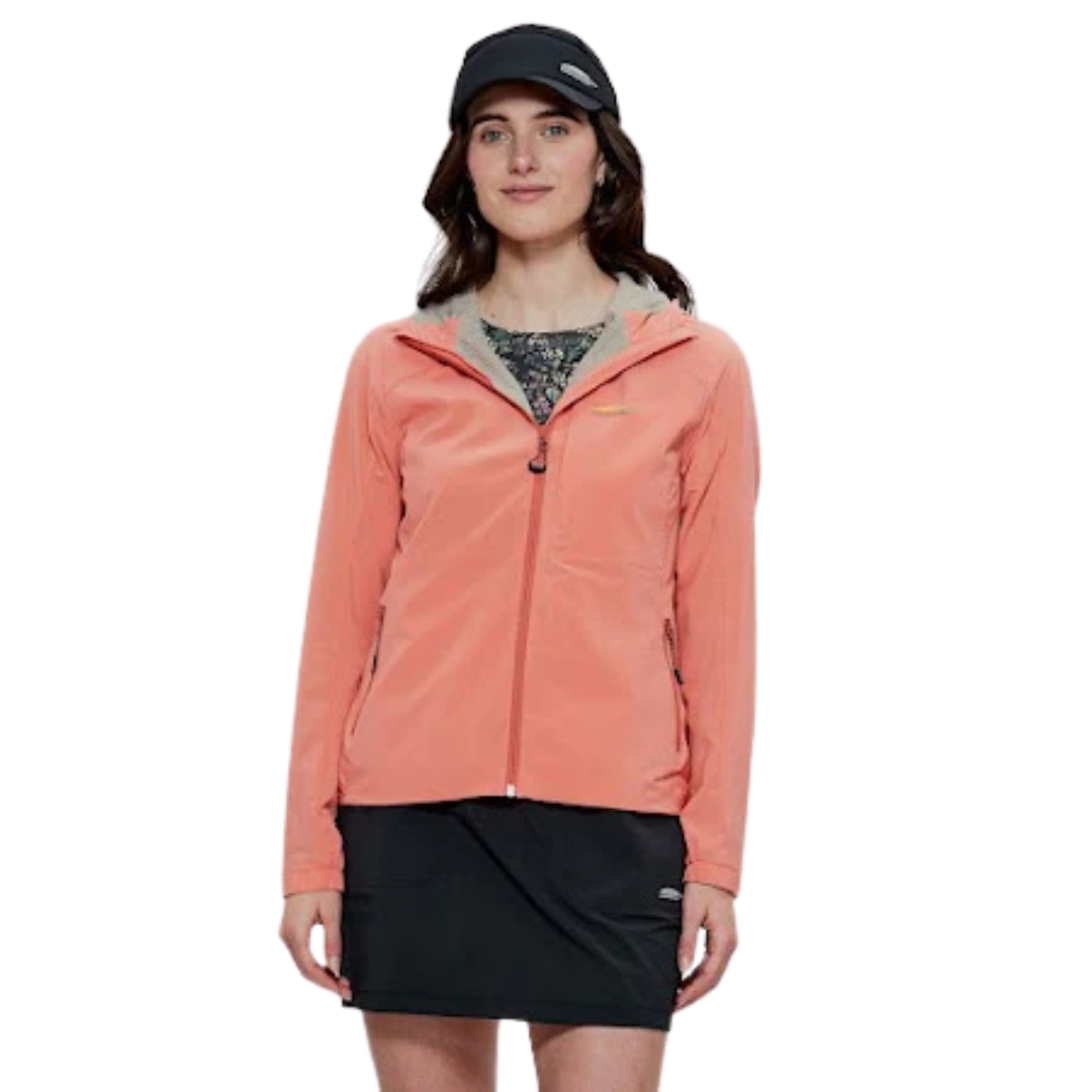 Une personne portant une veste corail, une jupe noire et une casquette noire se tient debout sur un fond blanc uni. La veste a une capuche et des fermetures éclair.