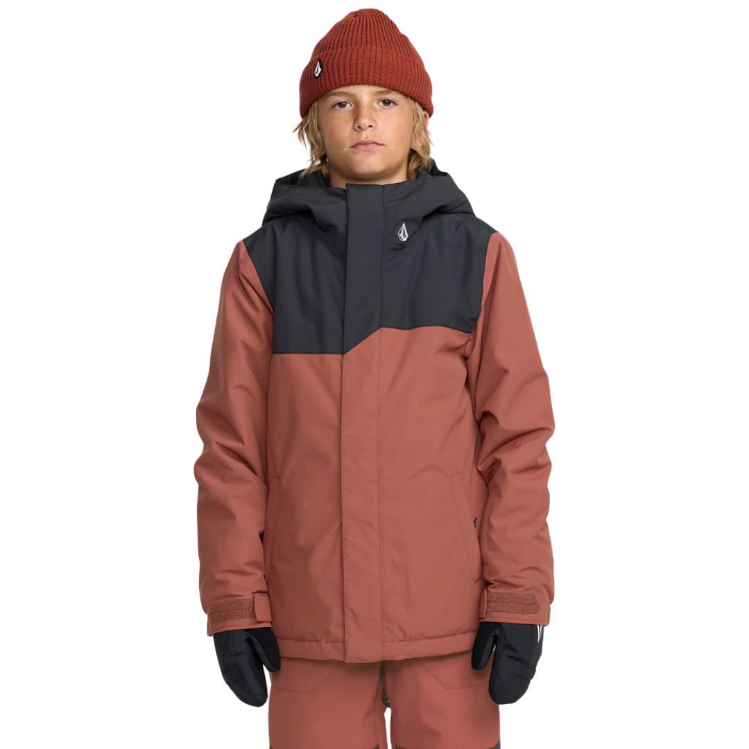 Une jeune personne portant la veste STONE.91 INS JACKET de couleur rouille avec un pantalon assorti, un bonnet en tricot, des gants noirs et une cagoule, sur un fond blanc uni.
