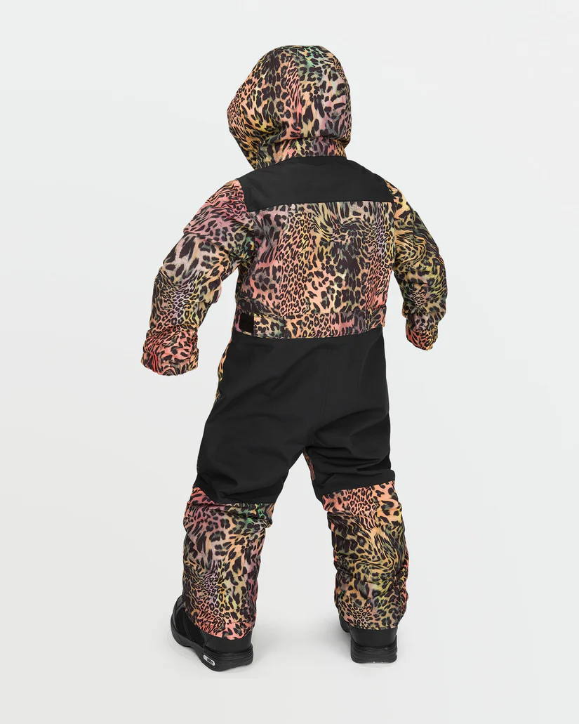 Un enfant porte une combinaison de neige colorée à imprimé léopard avec des touches de noir. La capuche est relevée et il est habillé de bottes d'hiver. L'arrière-plan est blanc uni.