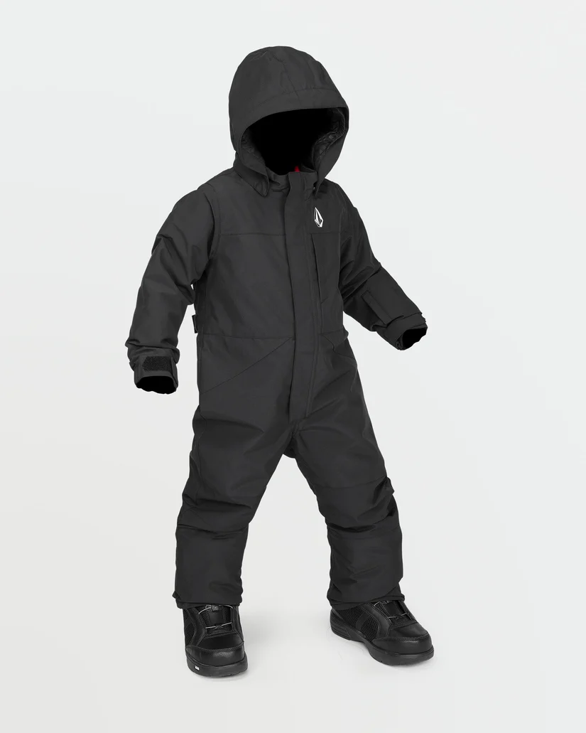 Un enfant porte une combinaison d'hiver noire avec une capuche et des bottes noires. La combinaison a une fermeture à glissière sur le devant, un petit logo sur la poitrine et couvre l'enfant de la tête aux pieds. L'enfant se tient debout sur un fond blanc uni.