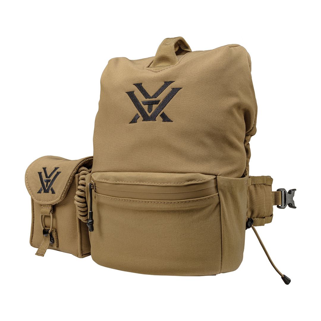 Un sac à dos de couleur beige avec une poche frontale zippée, une poche latérale attachée et un logo "VX" noir sur les deux compartiments, sur fond blanc.