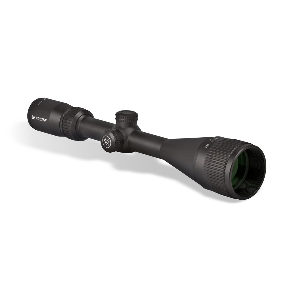 Une lunette de visée noire avec des boutons de réglage et un grand objectif, vue de biais sur un fond blanc. La lunette porte des marques et un marquage visibles sur son côté.