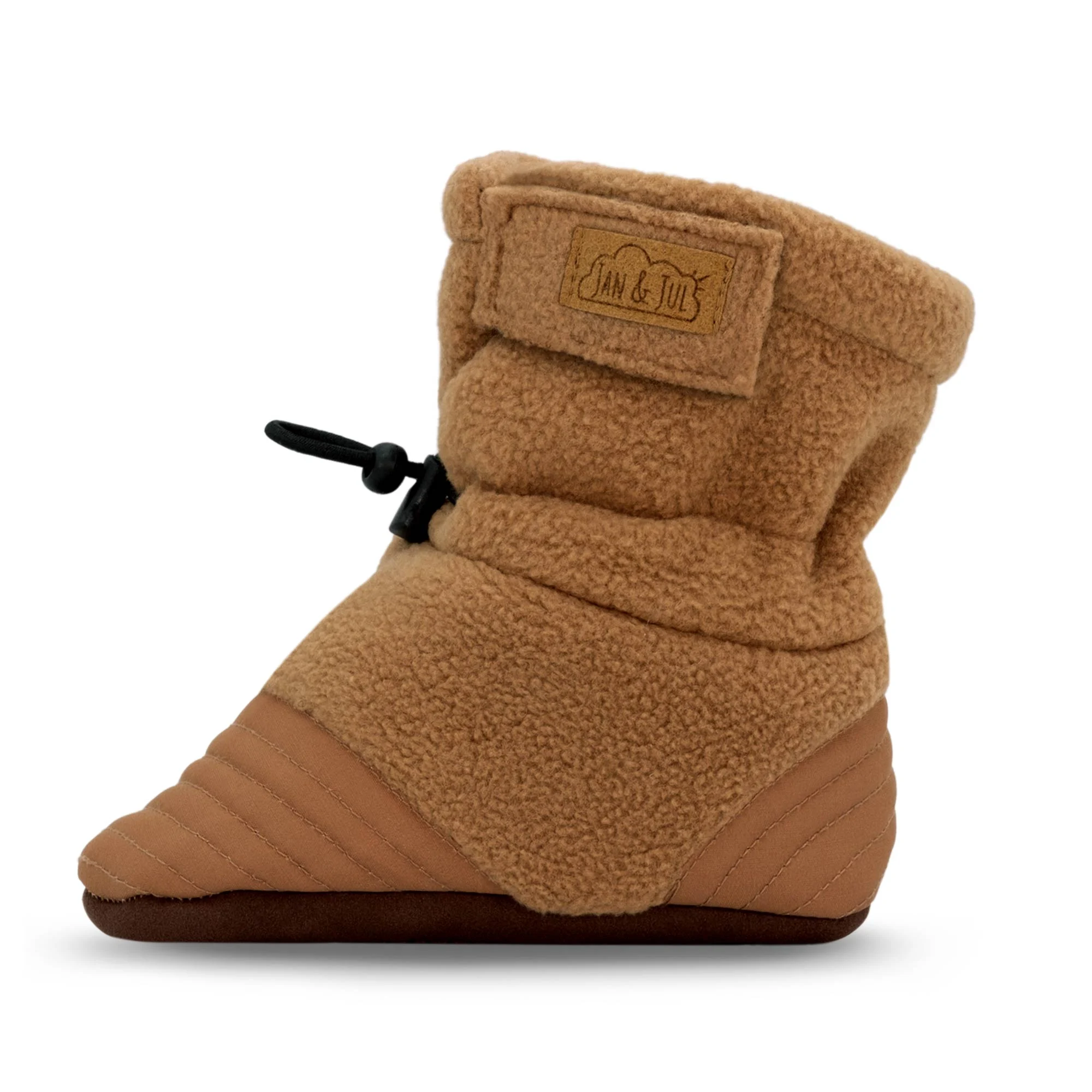 Une seule STAY-PUT COZY BOOTIE de couleur beige, avec un bout matelassé, une fermeture à genouillère réglable, une semelle souple et une étiquette "Jan & Jul" sur la manchette.